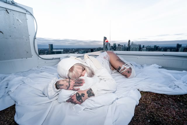 Casper lying on a white sheet on a Toronto rooftop with the city skyline behind